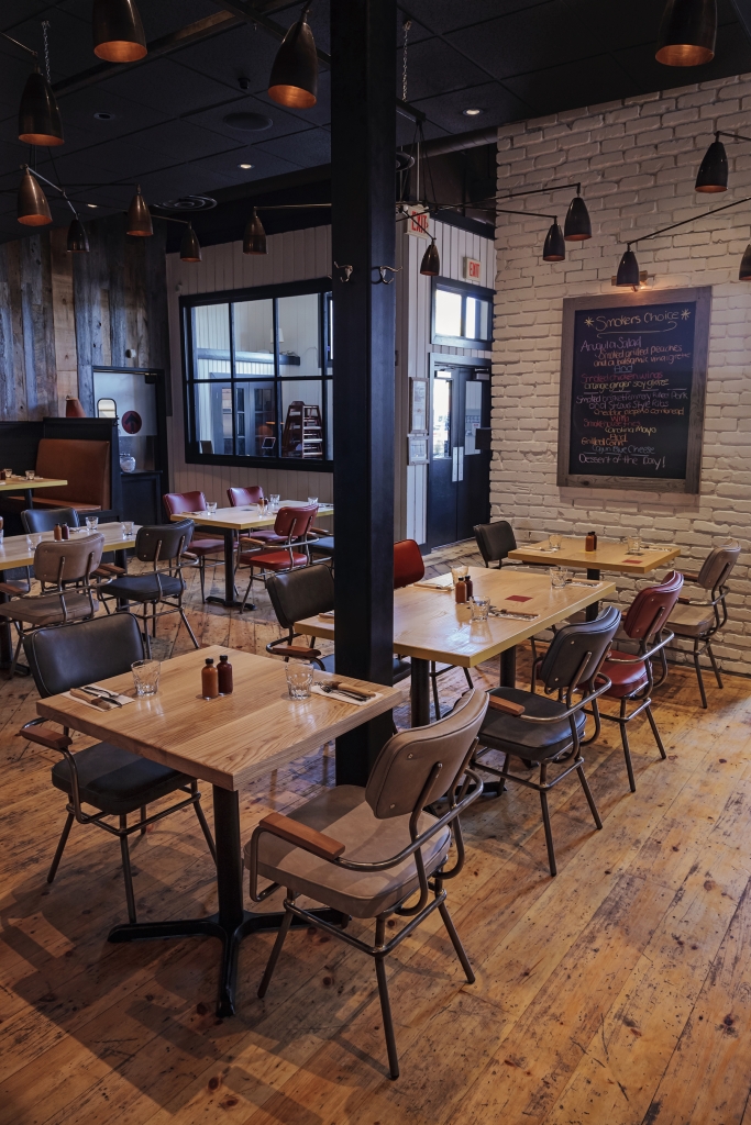 Barque Smokehouse surrounded by wooden tables and lounge chairs with three different colors
