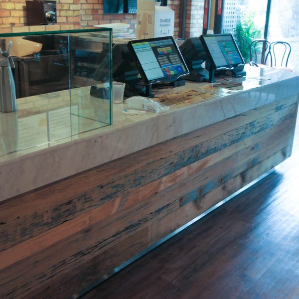 A different angle of the servery system with a wooden dinoc finish on the base, grey corian top, and two touch-screen point of sale machines on the counter.