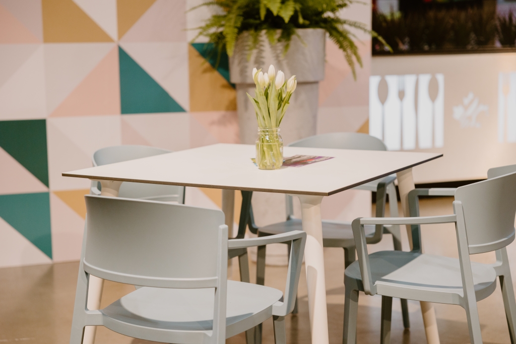 A white table with a small vase of white flowers and light blue armchairs surrounding it