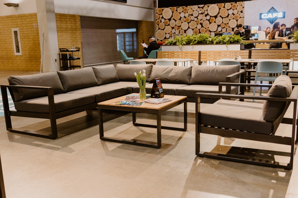 A grey lounge set surrounding a coffee table with wood slats and a black frame