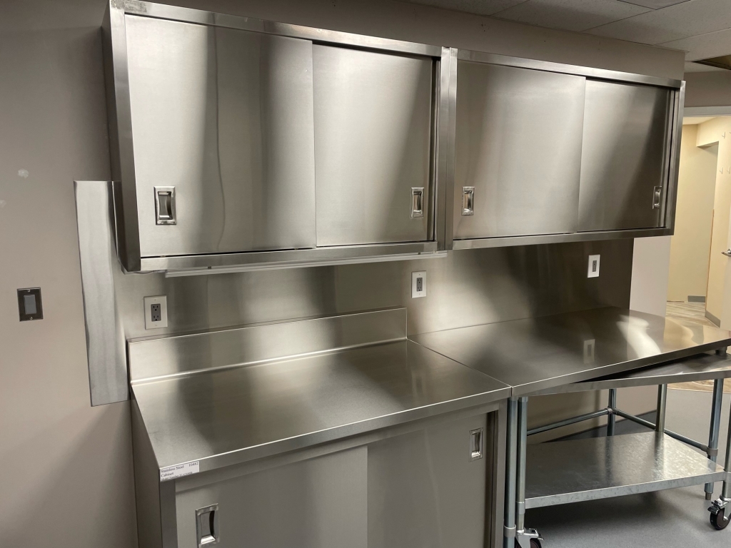 Stainless steel wall-mounted cabinets above a stainless steel cabinet and nested worktables