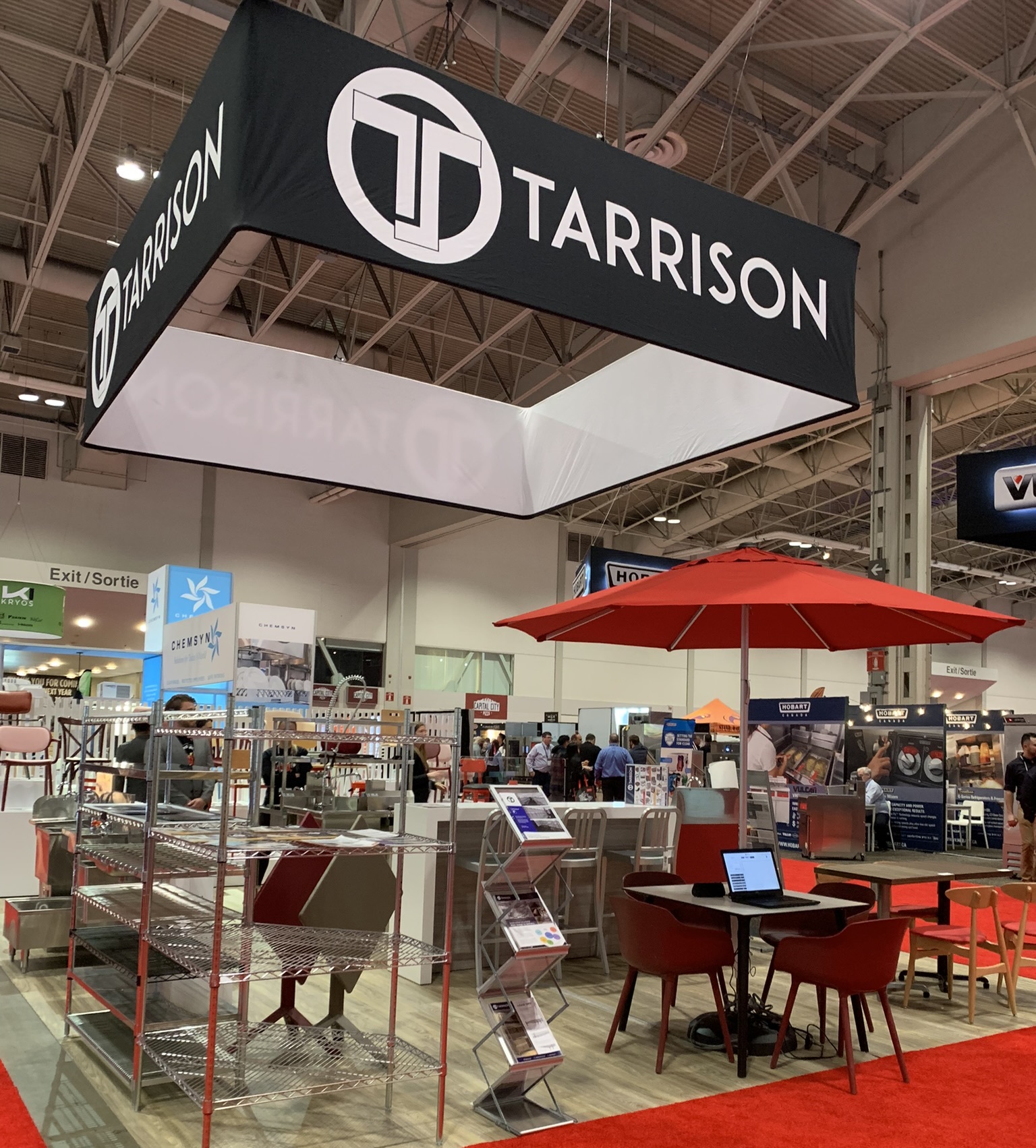 Tarrison's booth at the Restaurants Canada Show. Tarrison's hanging banner features prominently at the top of the image, while the stainless steel and furniture in the booth can be seen at the bottom of the photo